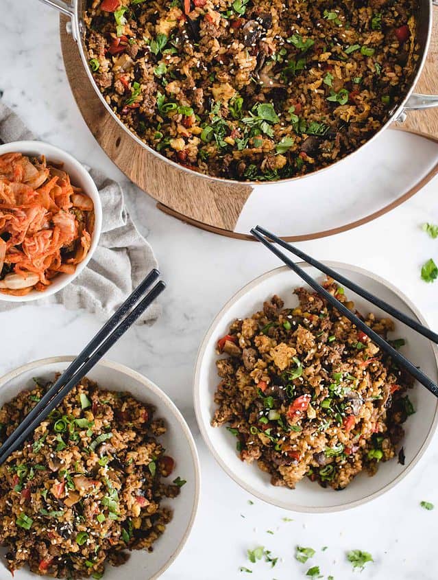 table with skillet of fried rice, kimchee and serving in bowl from overhead