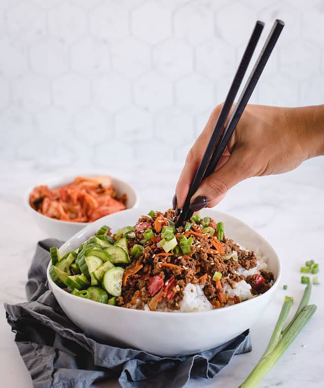 hand holding chopsticks, inserting into ground beef rice bowl
