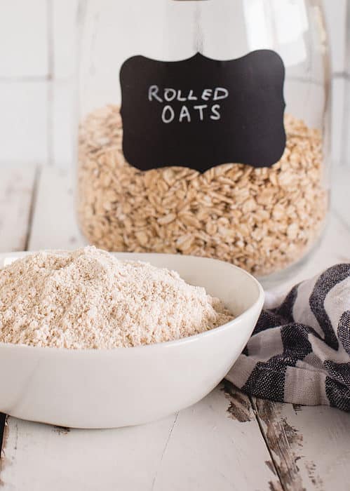 bowl of oat flour in front of a jar labeled rolled oats