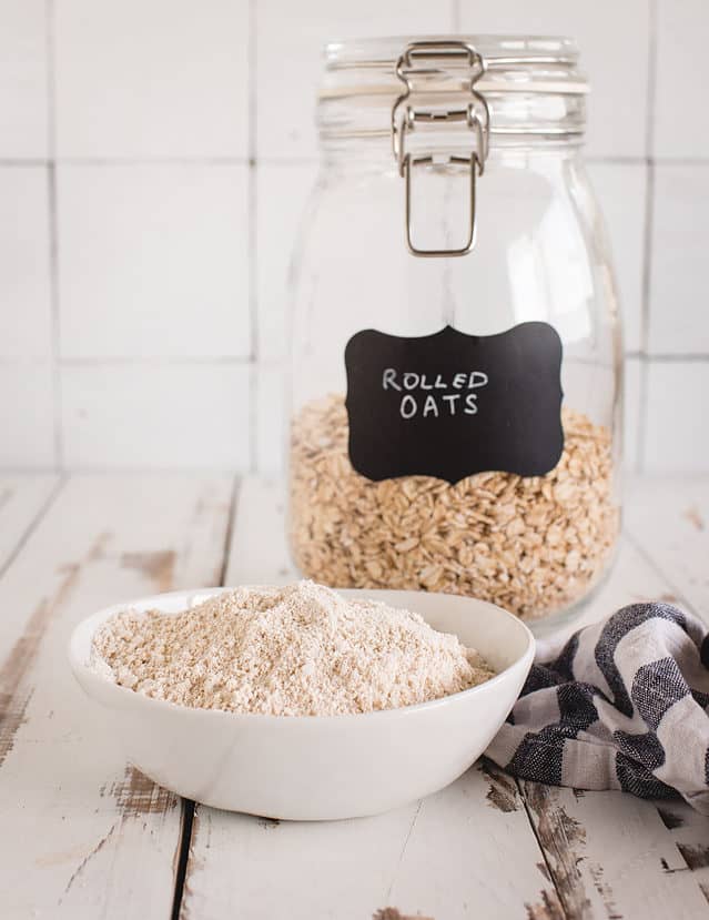 oat flour in a bowl in front of a jar of rolled oats 