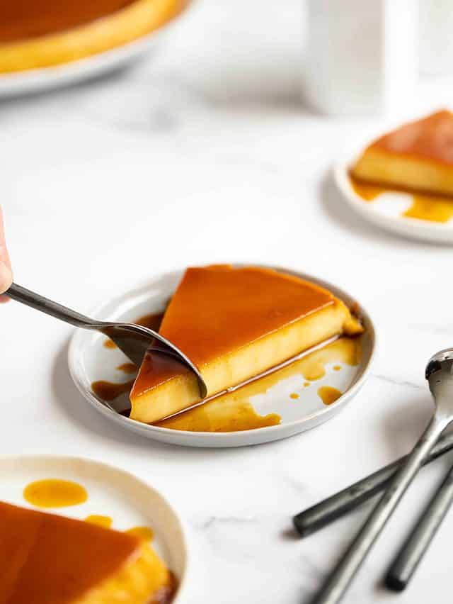 Slice of flan on a white plate with spoon