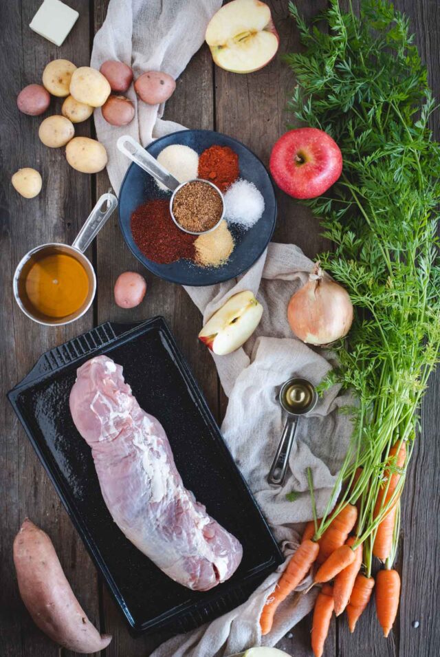 pork tenderloin with vegetables, apples and other raw ingredients laid out