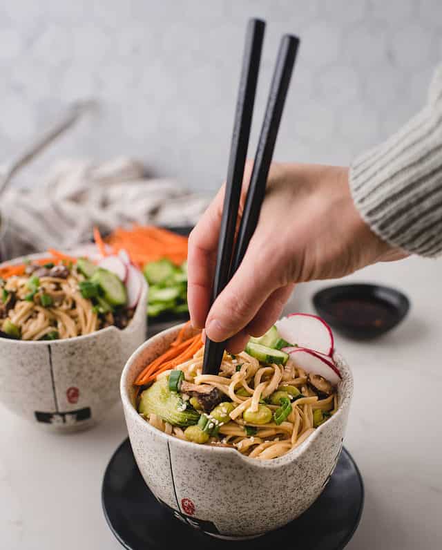 hand inserting chopsticks into bowl of miso noodles