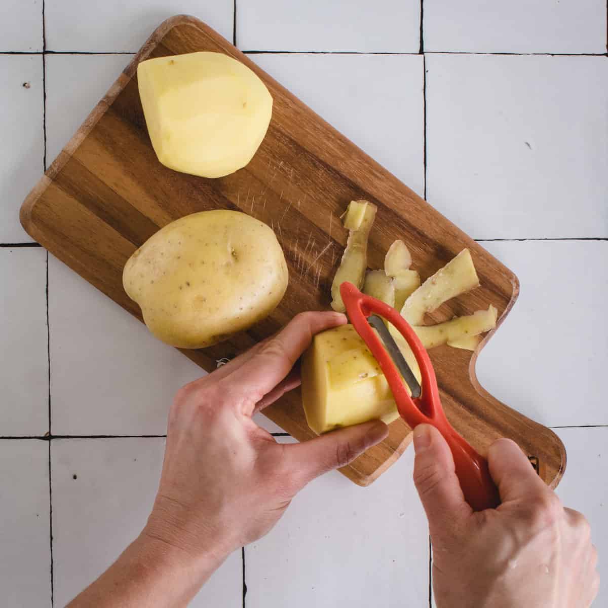 Hands peeling a yellow potato