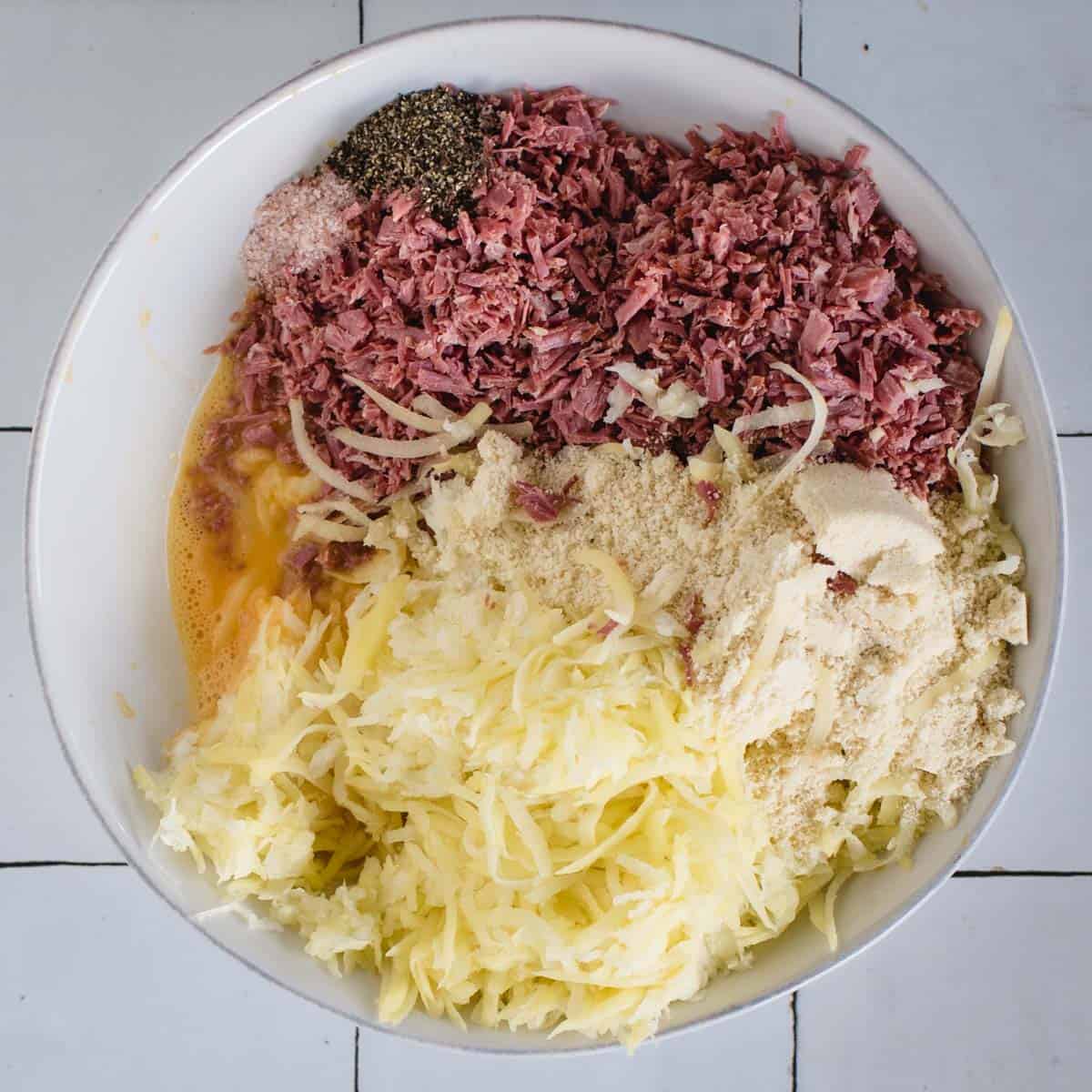 Bowl with corned beef, potato and other fritter ingredients before mixing
