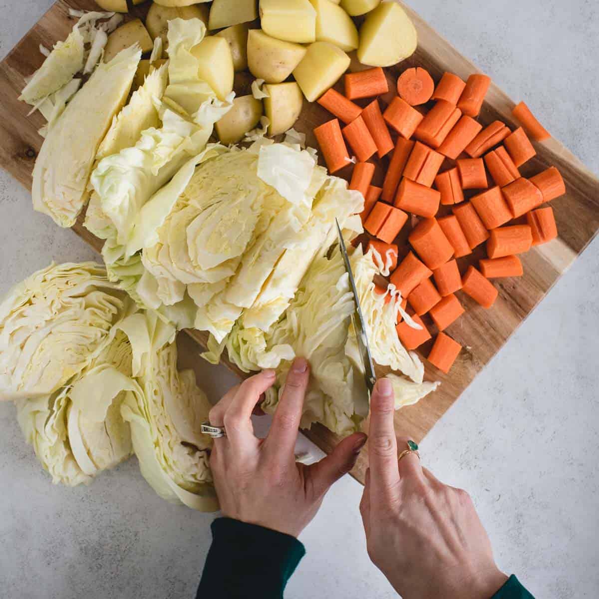 Hands cutting cabbage, carrots and potatoes