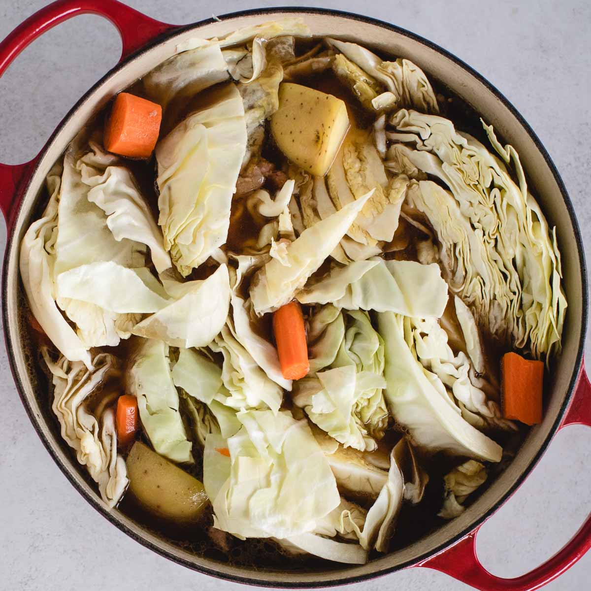cabbage, potatoes and carrots in a large pot with broth