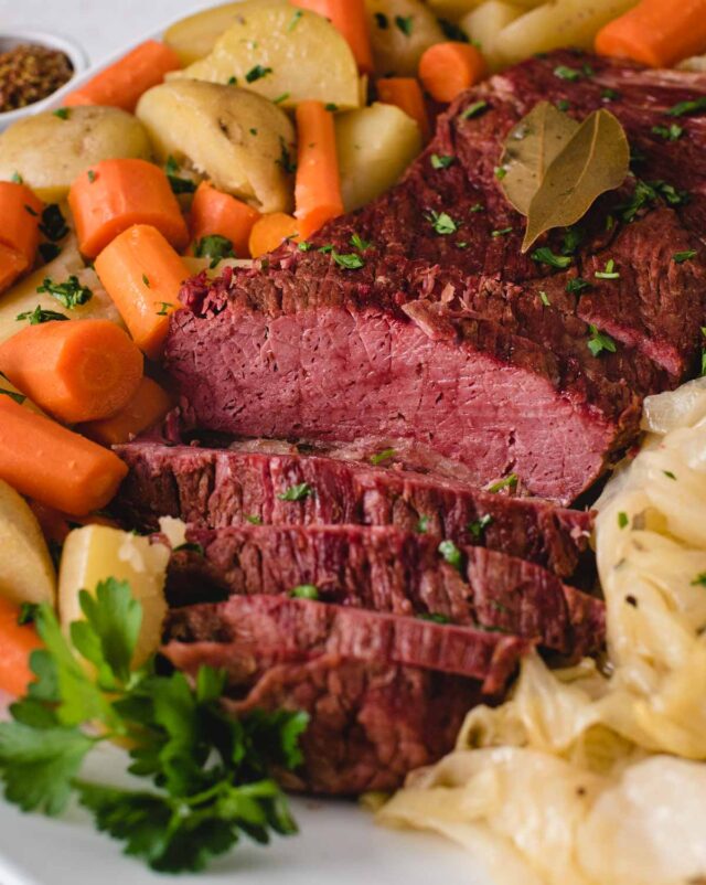 side view vertical of sliced corned beef on a serving platter with vegetables