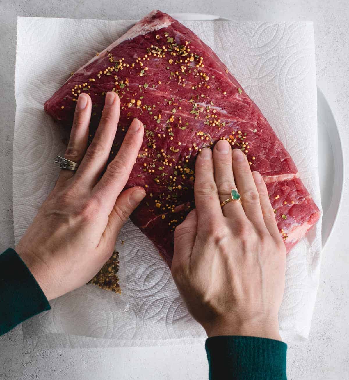 Hands rubbing spices onto corned beef