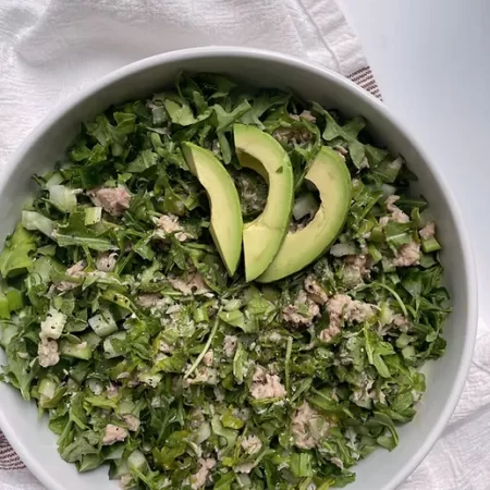 green salad in a bowl with tuna chunks and avocado on top