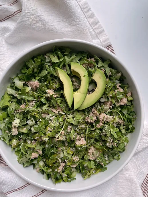 green salad in a bowl with tuna chunks and avocado on top