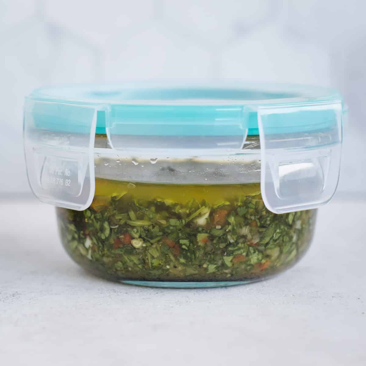 Fresh herb sauce with a layer of oil on top in a jar with a tightly fitting lid.
