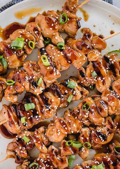 teriyaki chicken skewers from overhead on with green onion and sesame seeds sprinkled on top