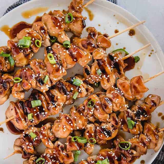 teriyaki chicken skewers from overhead on with green onion and sesame seeds sprinkled on top