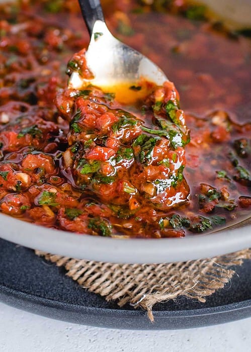 close up of spoonful of red chimichurri sauce