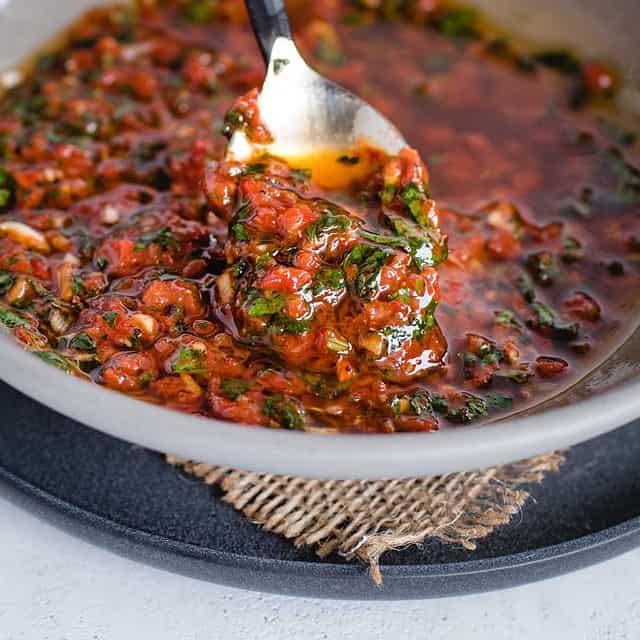 close up of spoonful of red chimichurri sauce