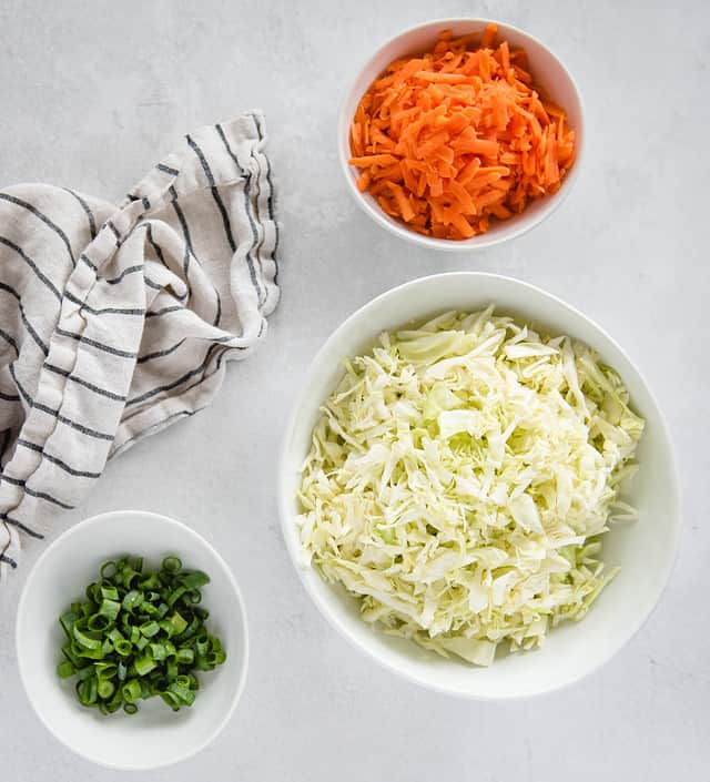 White bowls of cabbage, carrots, and green onion
