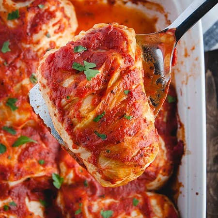close up of cabbage roll being lifted up from casserole dish