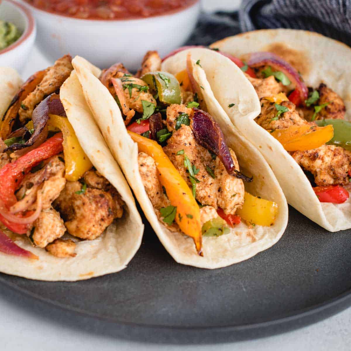 close up side view of 3 chicken fajitas on a plate