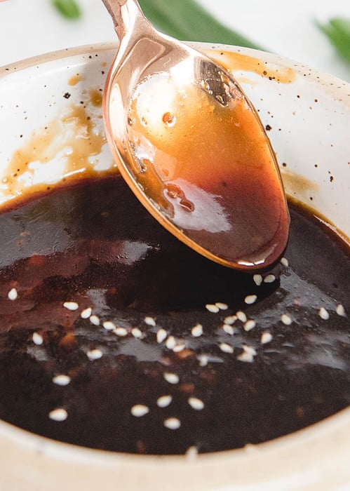 vertical side view of homemade gluten free teriyaki sauce being lifted from a bowl by a spoon