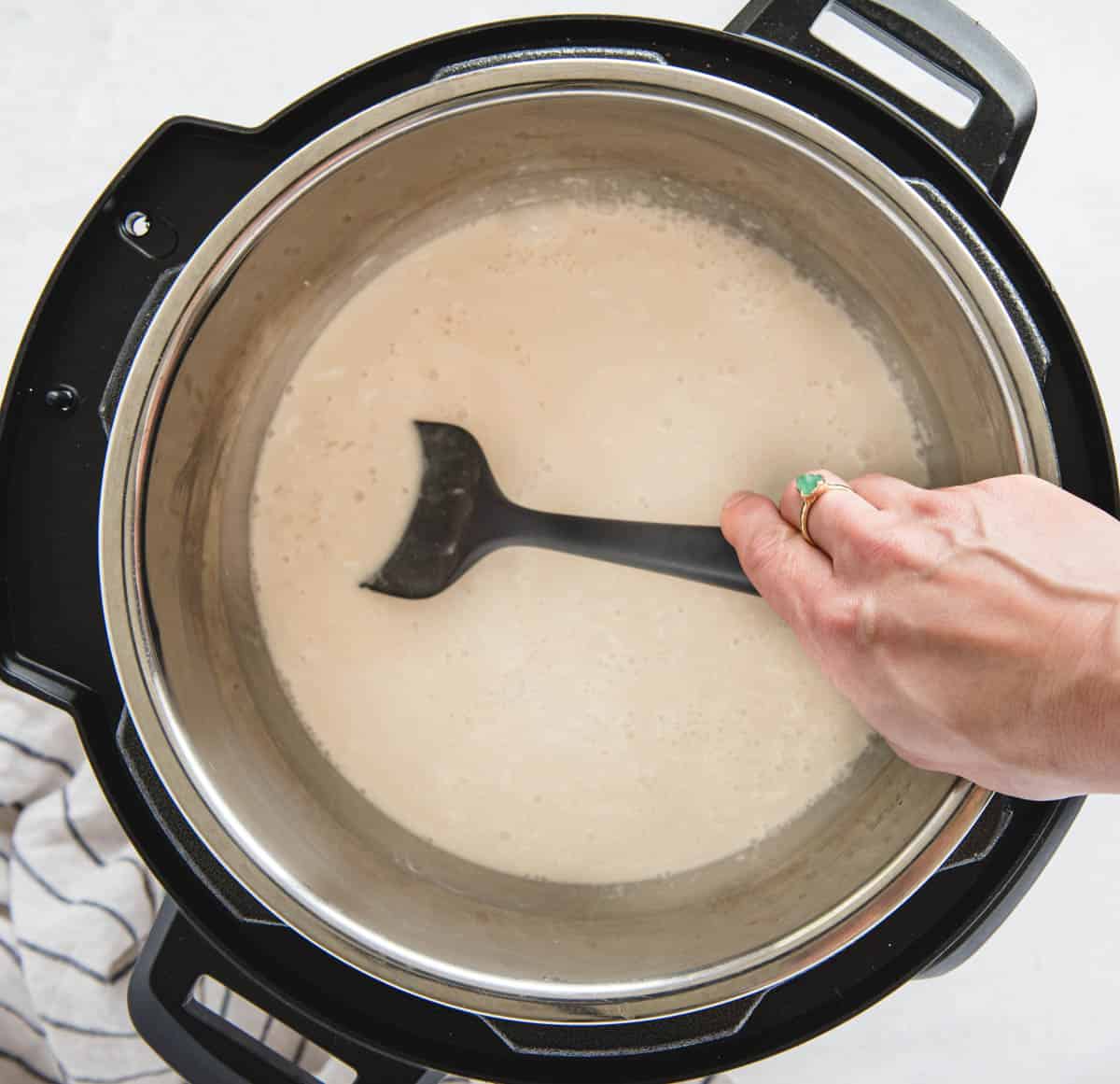 hand stirring in uncooked rice in instant pot