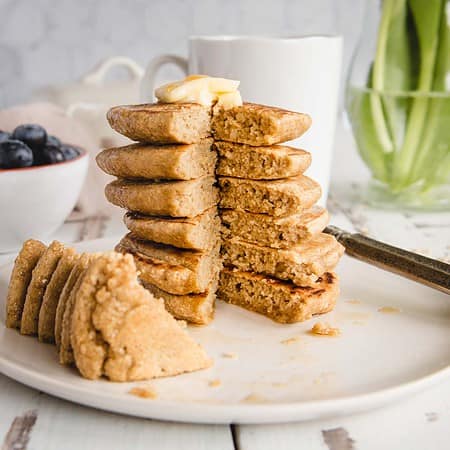 close up side view of stack of oat flour pancakes with a wedge taken out
