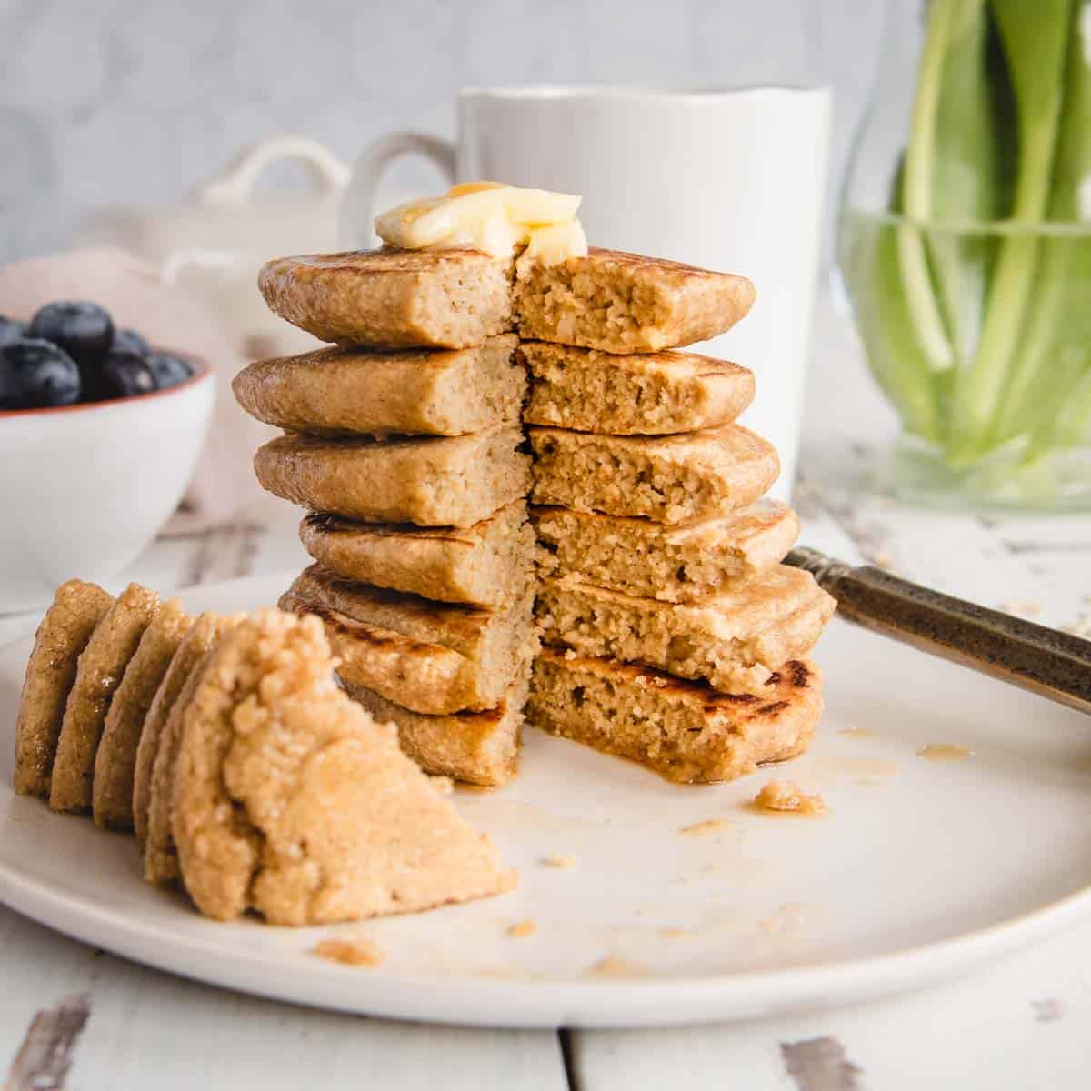 close up side view of stack of oat flour pancakes with a wedge taken out