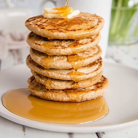 stack of oat flour pancakes with syrup being drizzled on top