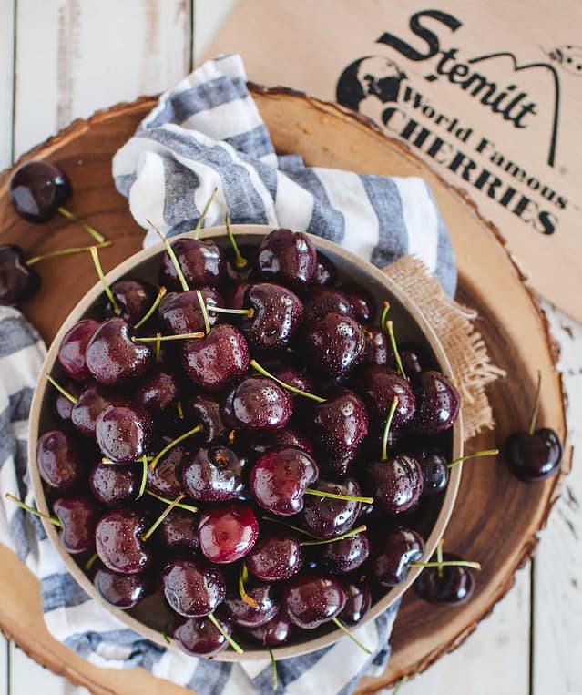 cherries in a bowl with brand logo in background