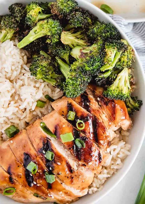 sliced marinated teriyaki chicken in a bowl with rice and broccoli from overhead