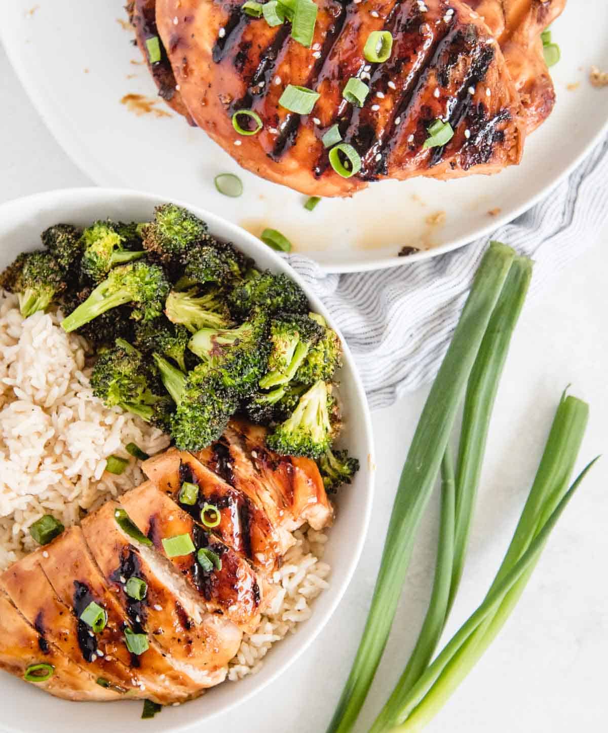 vertical of marinated sliced teriyaki chicken in a bowl with rice and broccoli from overhead