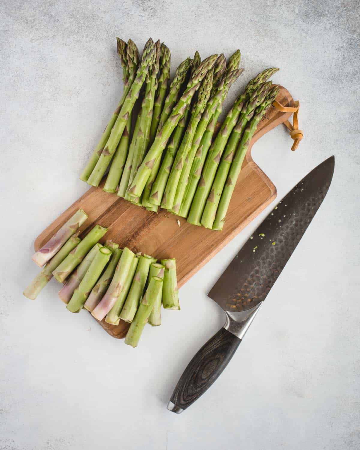 asparagus on a cutting board with bottoms freshly trimmed off