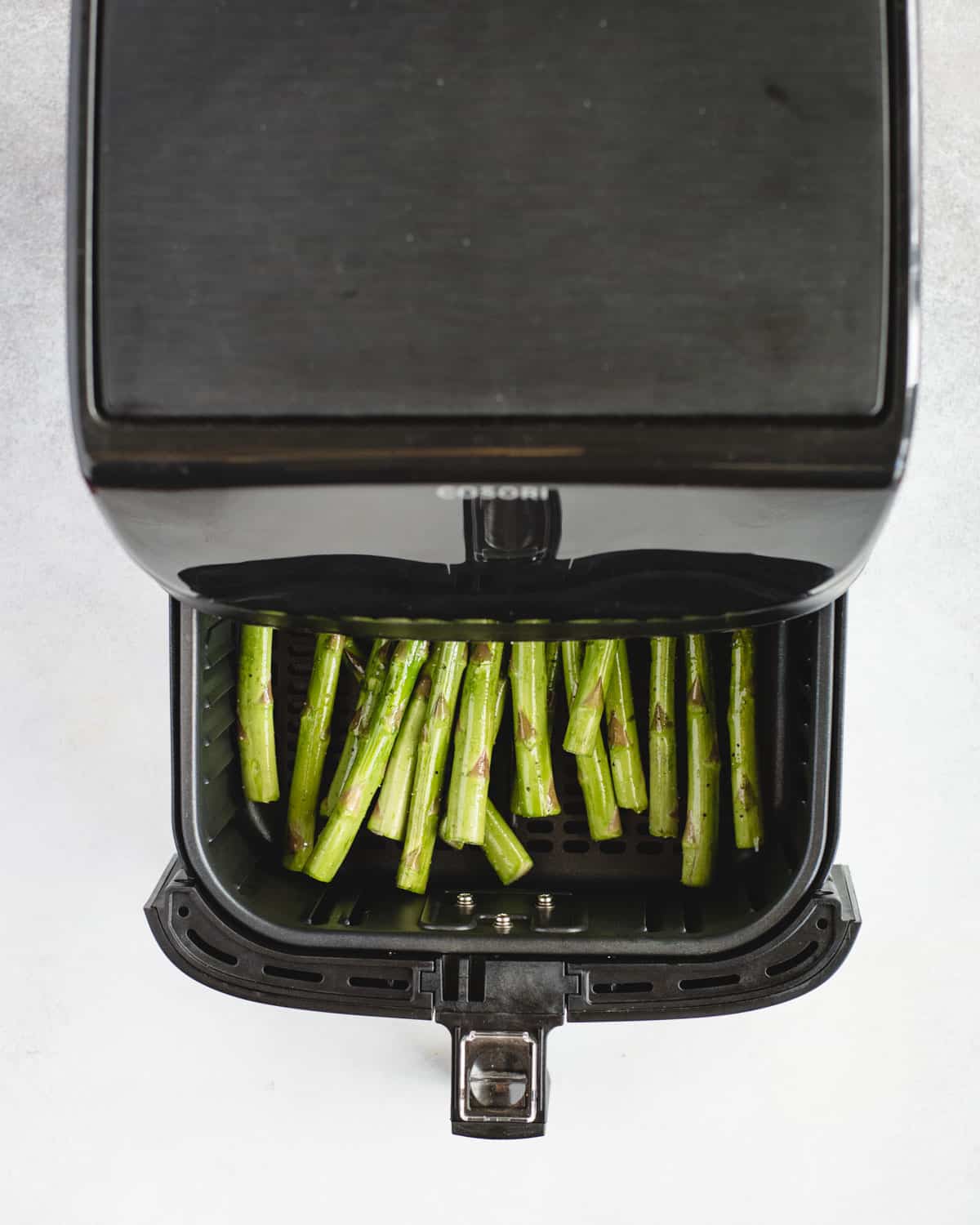 air fryer basket pulled out with asparagus in it
