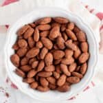 bowl of cocoa roasted almonds dusted with cocoa powder from overhead on white background