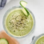 avocado cucumber green smoothie from overhead angle with hemp hearts sprinkled on top on white background
