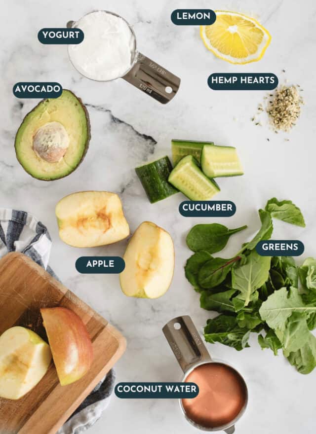 green avocado cucumber smoothie ingredients from overhead on white marble background