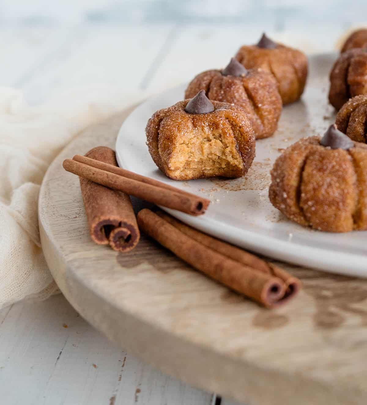 pumpkin energy ball with a bite taken out of it on a plate next to more protein balls