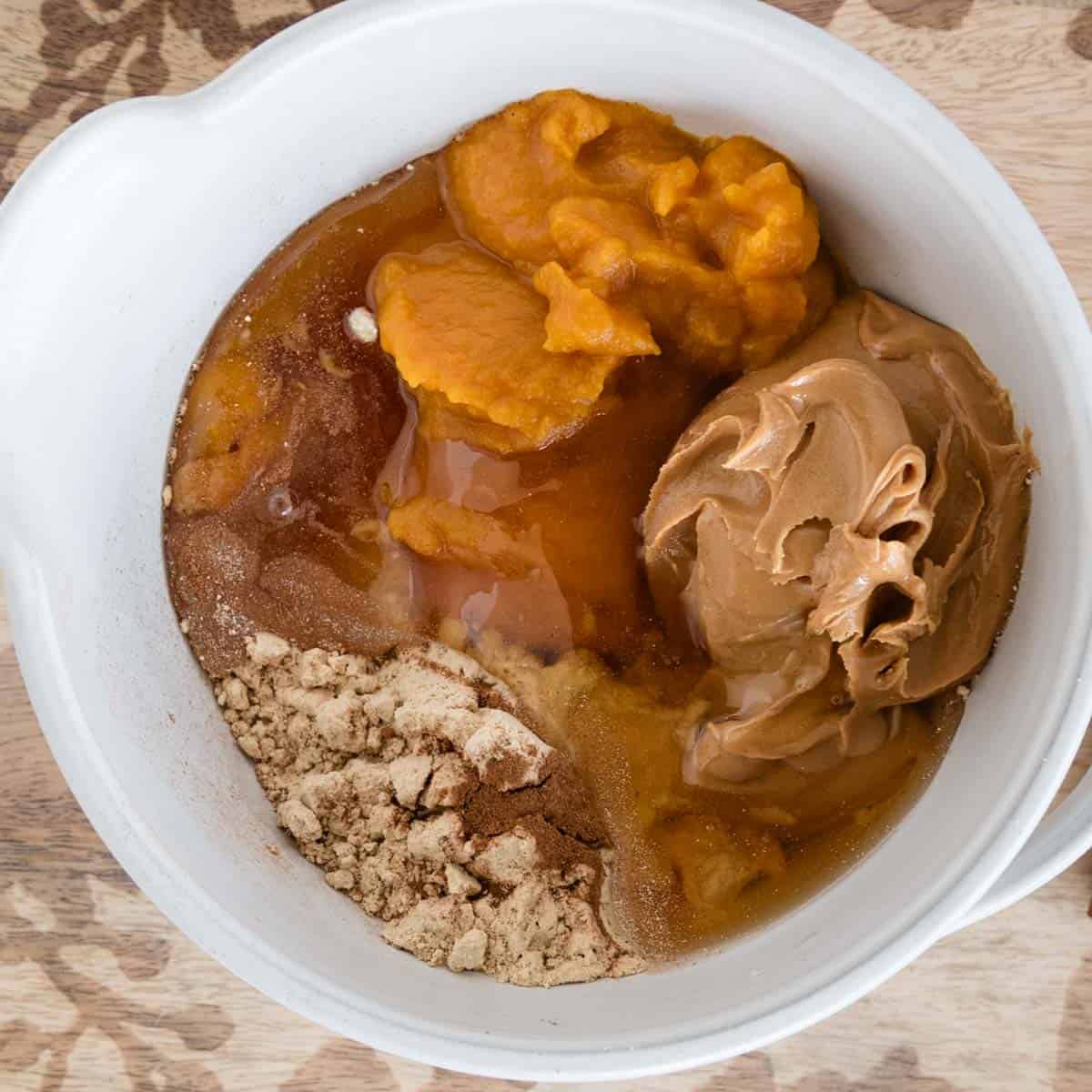 bowl with pumpkin, oat flour, peanut butter and other unmixed ingredients