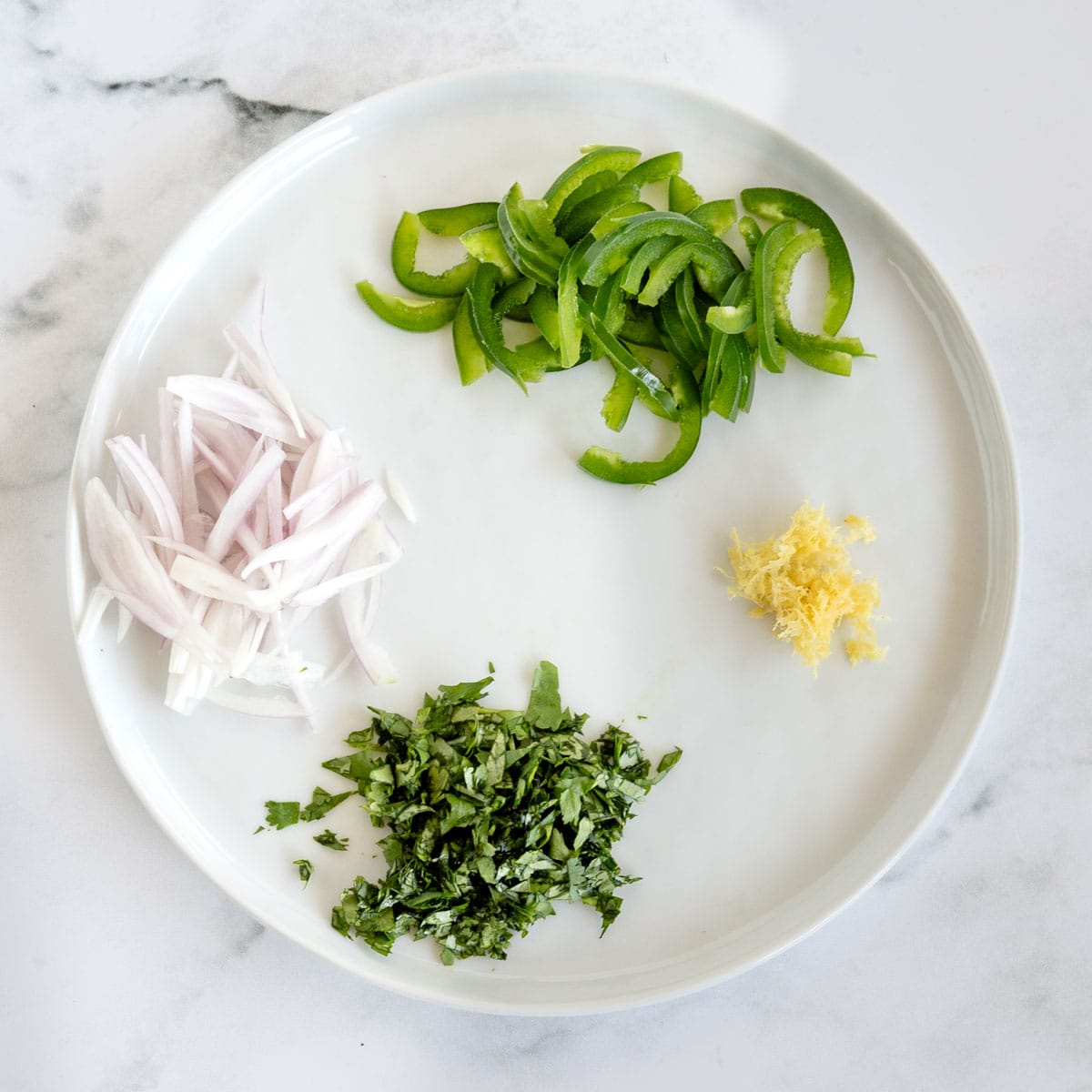 white plate with sliced shallot and jalapeno, lemon zest and chopped cilantro on it