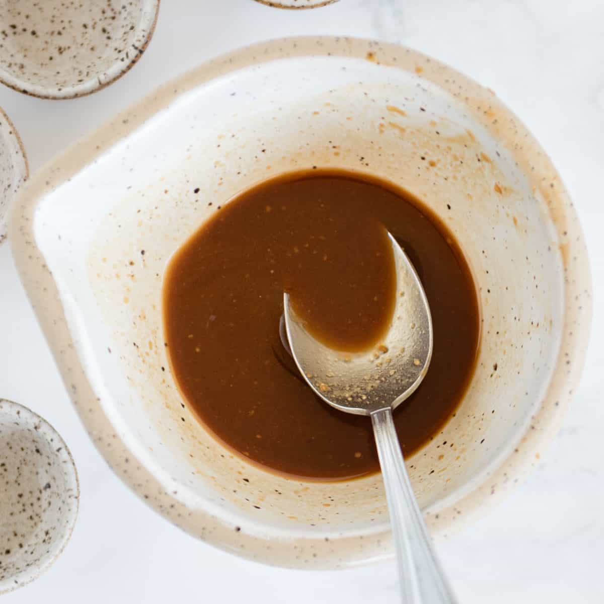 soy sauce dressing in a stoneware bowl with a spoon in it