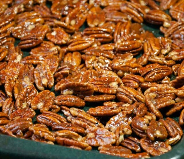 pecans tossed in spices on a sheet pan before roasting