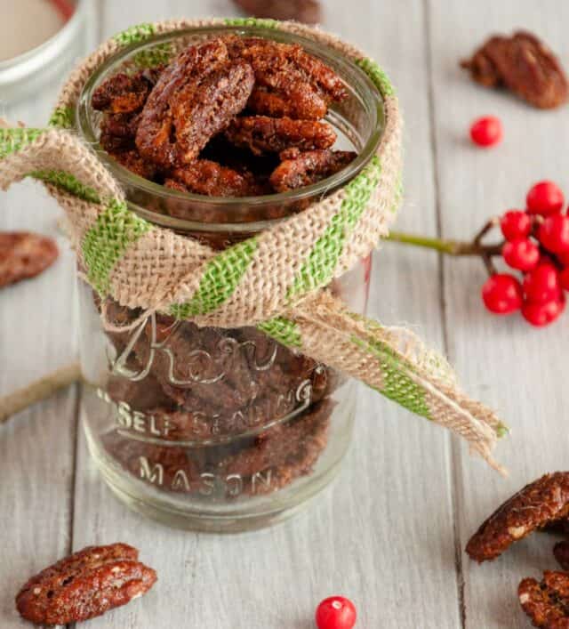 spiced pecans in a glass jar with a bow on it