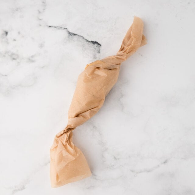 parchment paper rolled up and twisted at both ends with butter inside