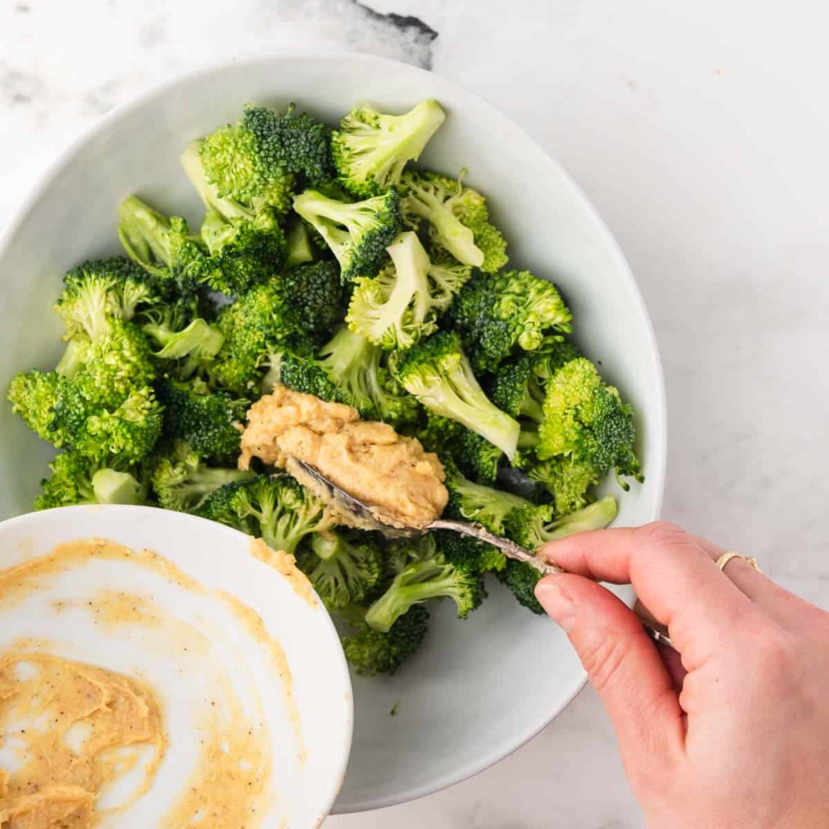 miso butter being spooned onto a bowl of broccoli