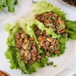 Asian style ground beef lettuce wraps with carrot and green onion on a white plate and backround