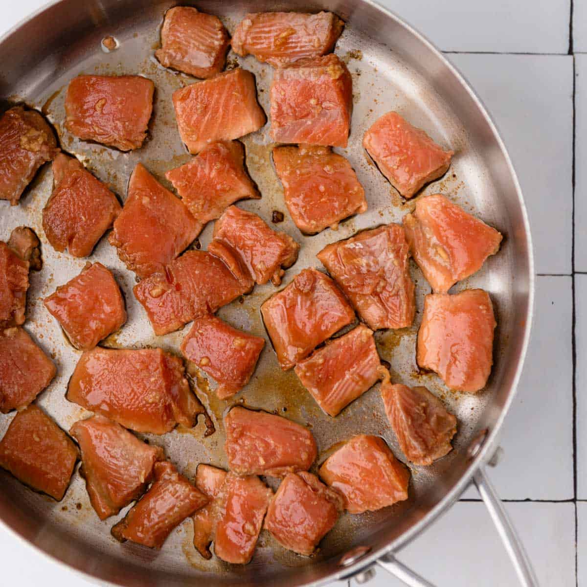 salmon pieces cooking in a skillet from overhead