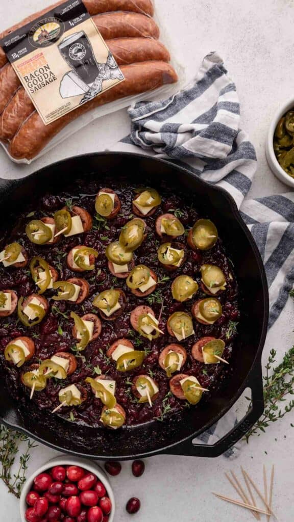 cast iron skillet with cranberry sausage toothpick appetizers next to package of ssausages