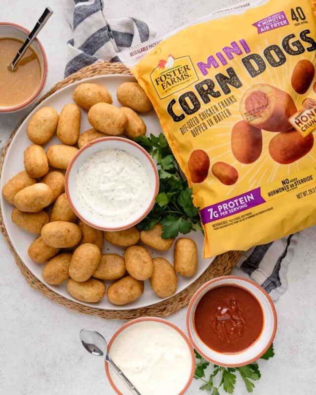 mini corndogs on a plate next to dipping sauces and Foster Farms product packaging bag