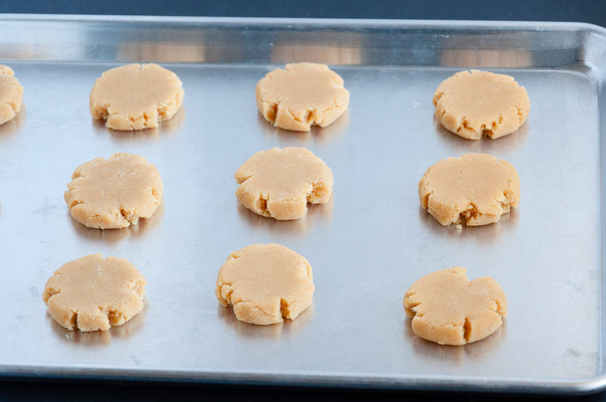 Ten unbaked cookies spaced out on a metal baking sheet, ready to go in the oven.
