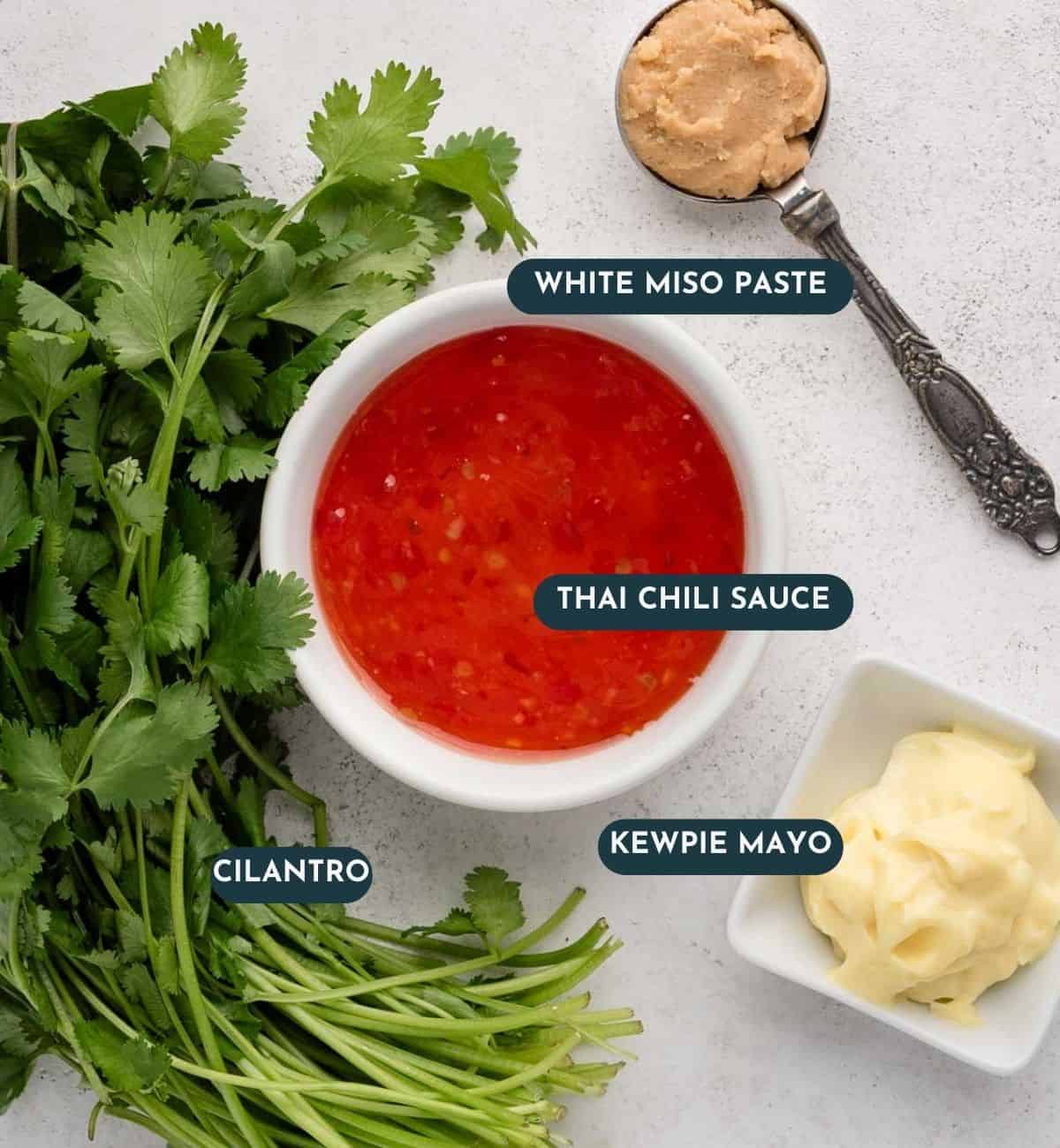 Cilantro, Thai chili sauce, kewpie mayo, and white miso paste arranged on a light surface with labels.